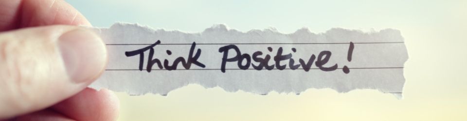 A hand holding a piece of paper that says 'think positive'